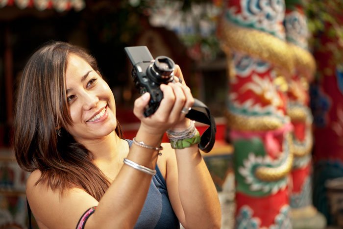Asian woman taking a photo with a camera.