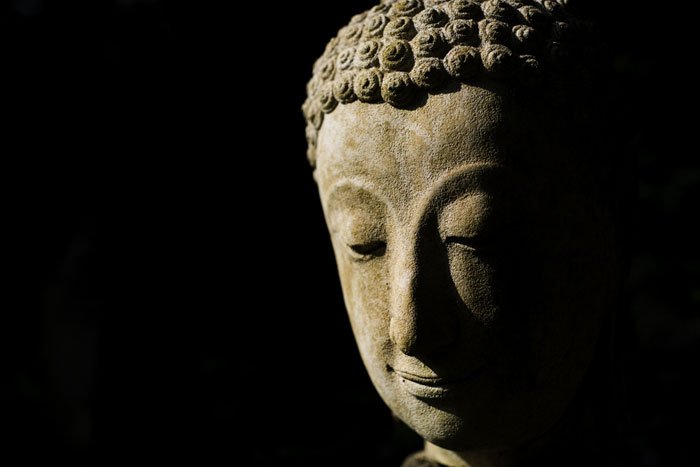 face of a Buddha statue is isolated by selective lighting and careful exposure against a dark background during a one day Chiang Mai Photo Tour