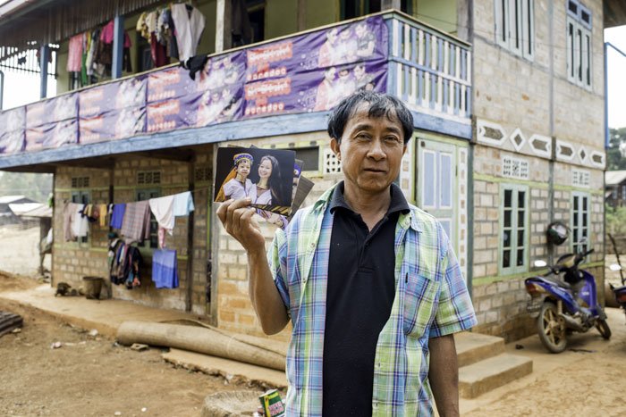 Kayan man in a village in Myanmar with a photo of his daughter and grand daughter
