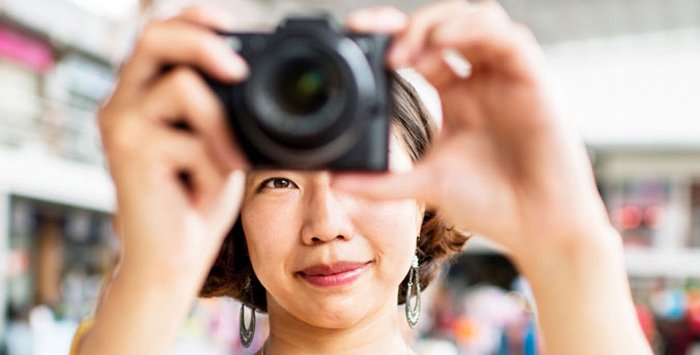 Asian woman taking a photo with a small camera